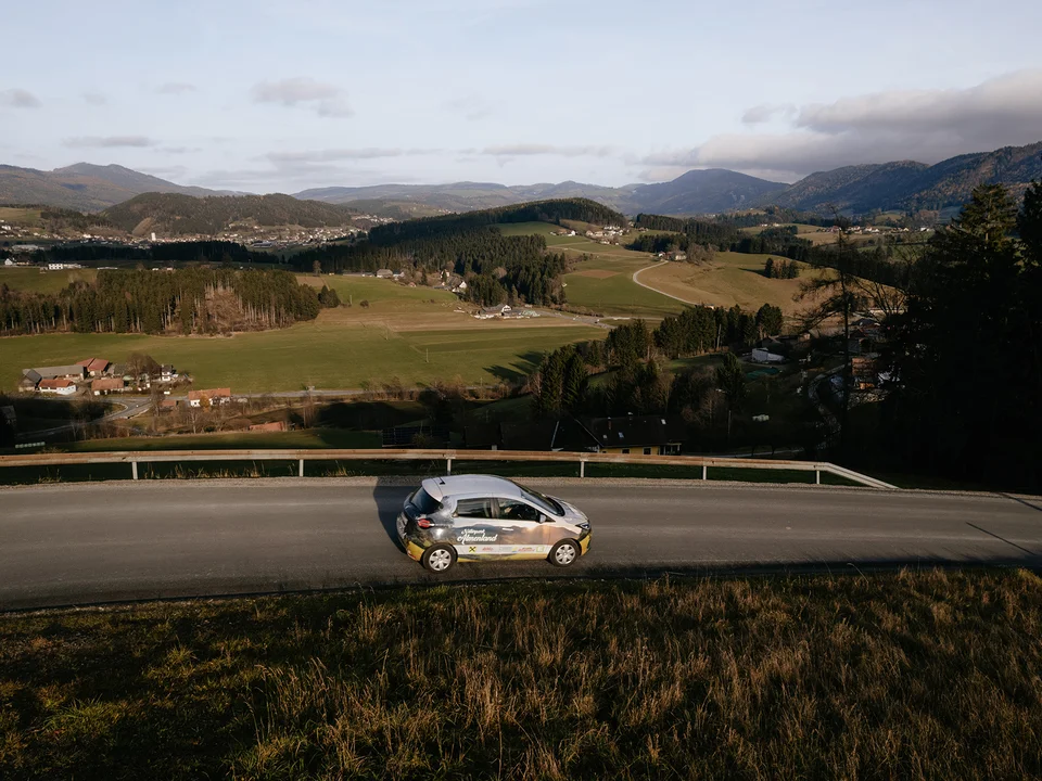 E-Auto mit Blick auf den Passailer Kessel im Naturpark Almenland. E-Auto mit Blick auf den Passailer Kessel im Naturpark Almenland.