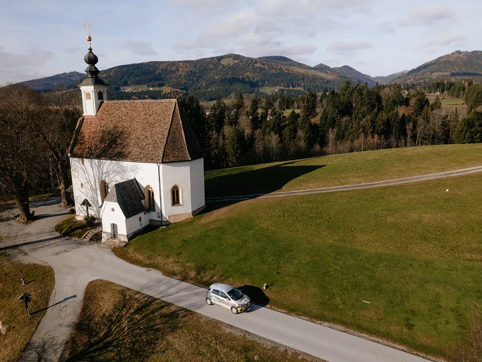 E-Auto mit der Lindenbergkirche in Passail. E-Auto mit der Lindenbergkirche in Passail.